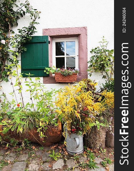 Facade of a farmers cottage with some wihtered flowers and cobblestone pavement in front