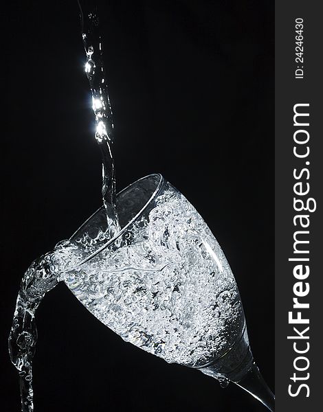 Sparkling water pouring into glass against a black background. Sparkling water pouring into glass against a black background