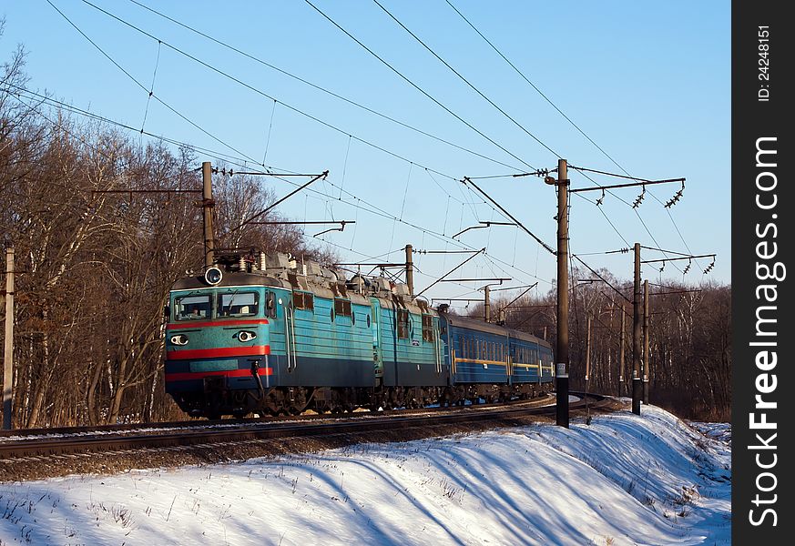 Electric locomotive with passenger cars on winter track