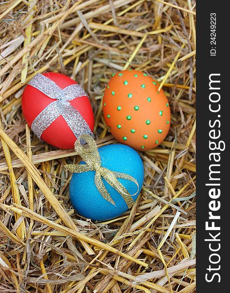 Three brightly colored Easter eggs on straw