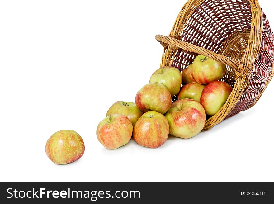 Apples pour out from a basket on a white background