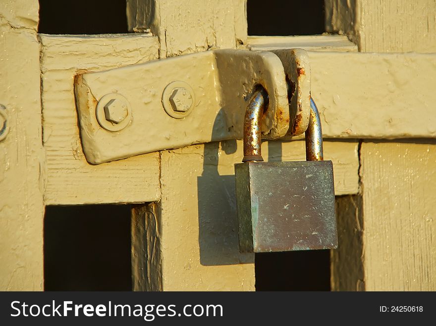 Rusty padlock closing a wooden yellow fence