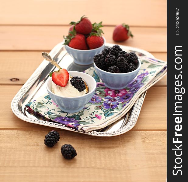 Strawberries and blackberry with mascarpone cream on a tray with a napkin