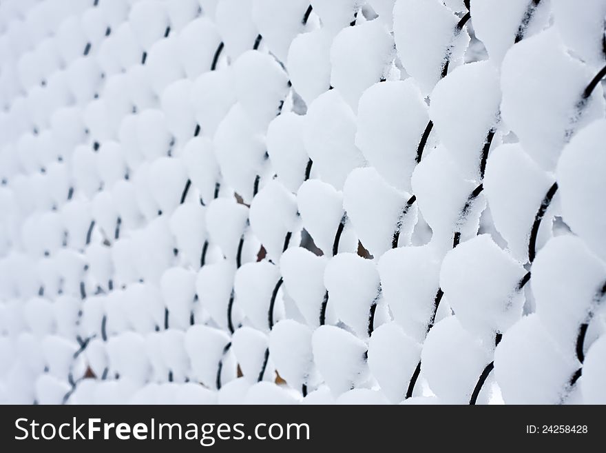 A fence made of mesh, after heavy snowfall. A fence made of mesh, after heavy snowfall.