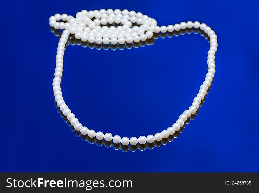 Necklace with white pearl on a blue background. Necklace with white pearl on a blue background