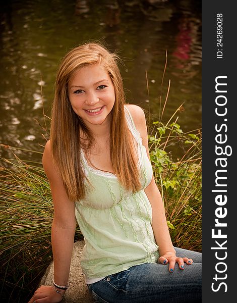 Teen girl sitting at pond