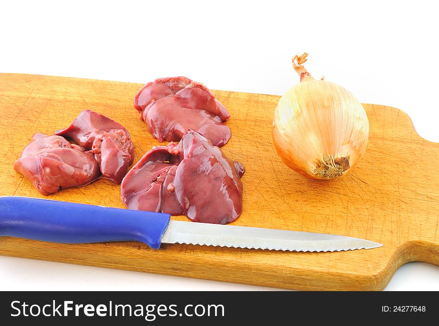 Fresh raw chicken liver lies on a wooden board next to the knife and onion. Fresh raw chicken liver lies on a wooden board next to the knife and onion