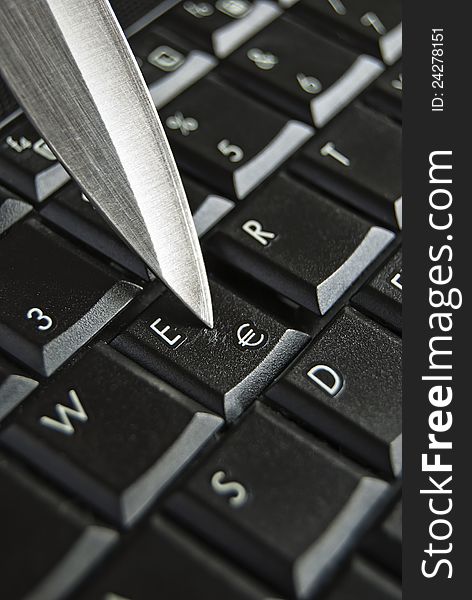 Knife blade pressing the euro symbol key on a computer black keyboard. Knife blade pressing the euro symbol key on a computer black keyboard.