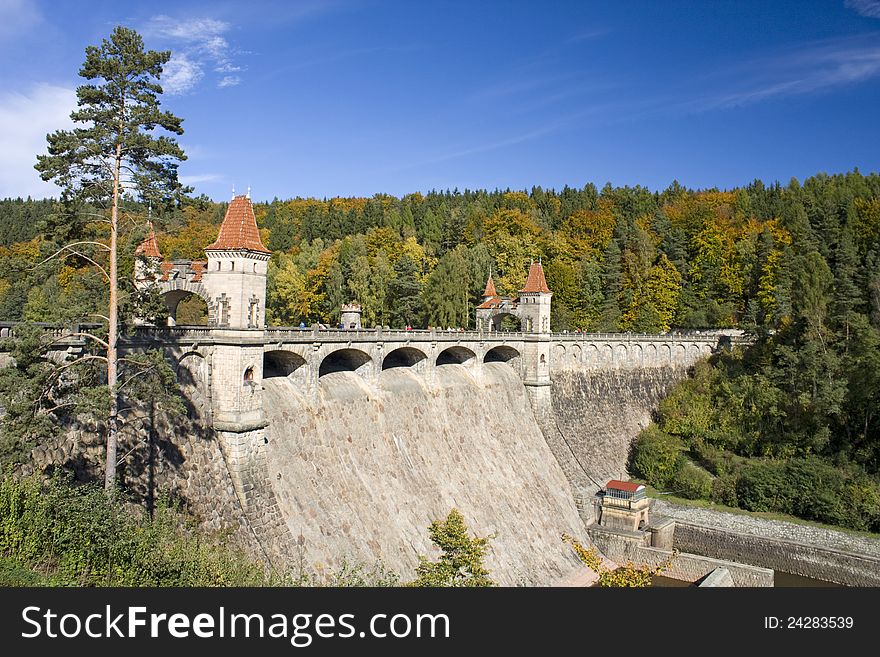 Stone dam in summer sunny day, water project status in forest landscape