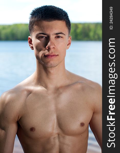 Muscled male model posing near the lake. Muscled male model posing near the lake