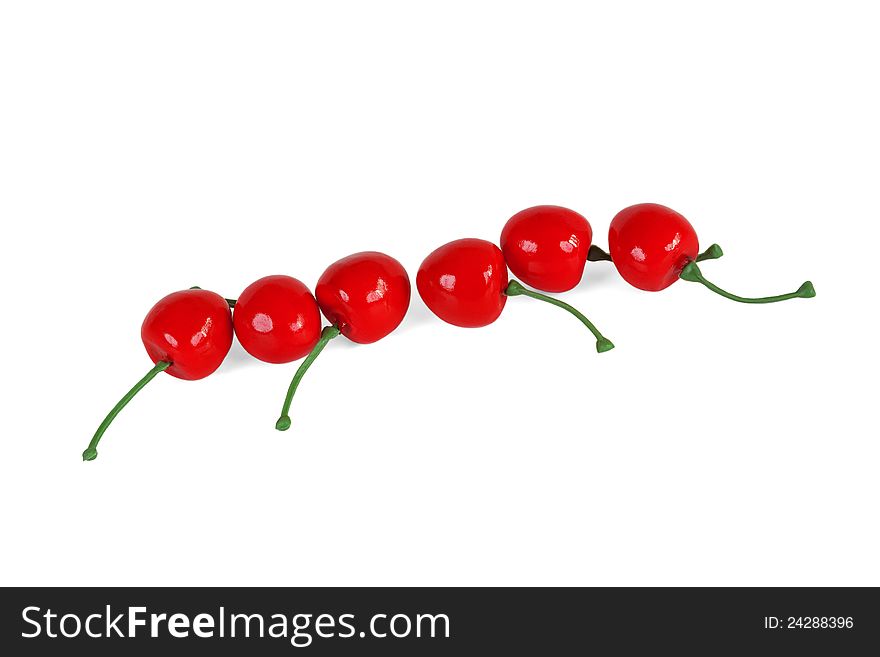 The red artificial cherries, lined in a row on a white background. The red artificial cherries, lined in a row on a white background