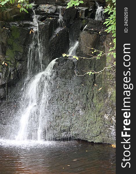 A Pretty Waterfall Flowing Over Rocks into a Pond. A Pretty Waterfall Flowing Over Rocks into a Pond.