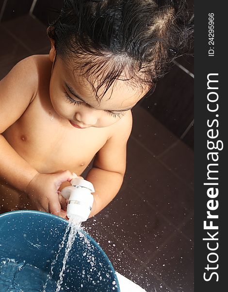 A little boy playing with water sprinkler in the bath room. A little boy playing with water sprinkler in the bath room.