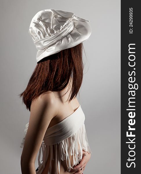 An image of a woman wearing a vintage white hat and white fringed top, turned away from the camera so her face isn't visible. An image of a woman wearing a vintage white hat and white fringed top, turned away from the camera so her face isn't visible