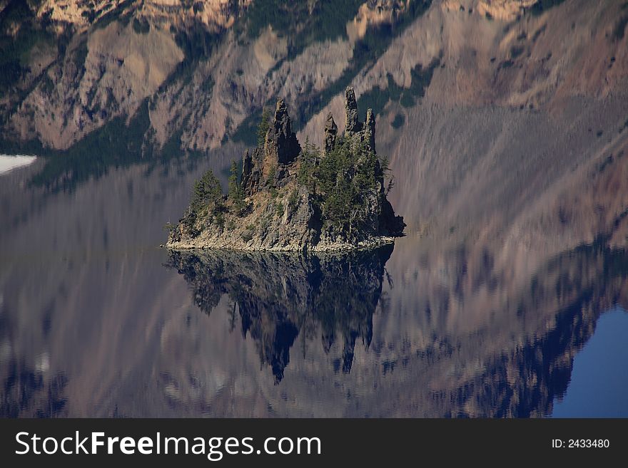 Phantom ship island. Island and mountain reflection in water. Crater lake