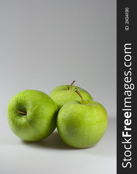 Three tasty green apples on grey background. Copyspace provided.