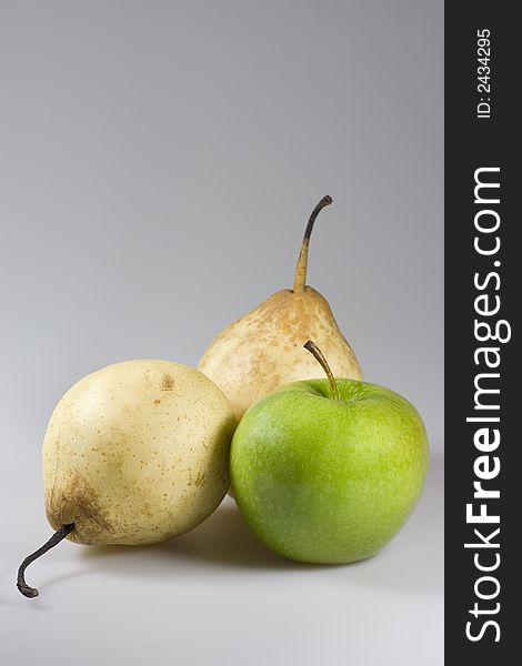 One green apple and two yellow chinese pears on grey background. Copyspace provided. One green apple and two yellow chinese pears on grey background. Copyspace provided.