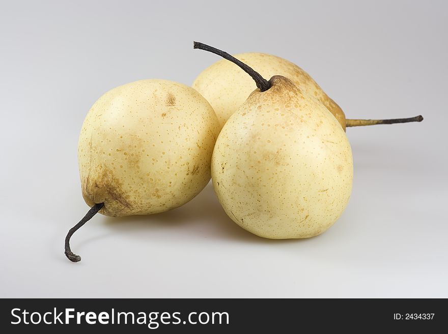 Three yellow chinese pears on grey background.