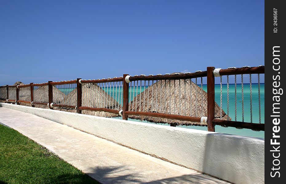 Sidewalk protected by a wooden and rope railing, overlooking the ocean near Playa del Carmin, Mexico. Sidewalk protected by a wooden and rope railing, overlooking the ocean near Playa del Carmin, Mexico.