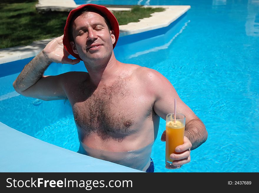 Man with drink in the pool enjoying sunlight. Man with drink in the pool enjoying sunlight