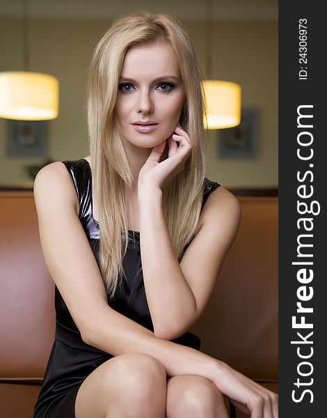 Attractive blond woman in black dress sitting on the couch