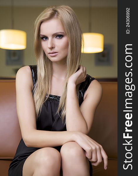 Attractive blond woman in black dress sitting on the couch