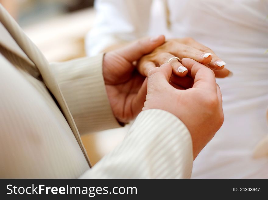 Groom putting a wedding ring on bride's finger. Groom putting a wedding ring on bride's finger