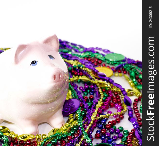 Pink piggy bank  with Mardi Gras colorful beads and coins. Pink piggy bank  with Mardi Gras colorful beads and coins