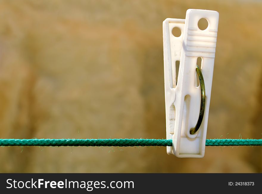 Clothespin hanging on a cord stretched the green, the background brown carpet. Clothespin hanging on a cord stretched the green, the background brown carpet