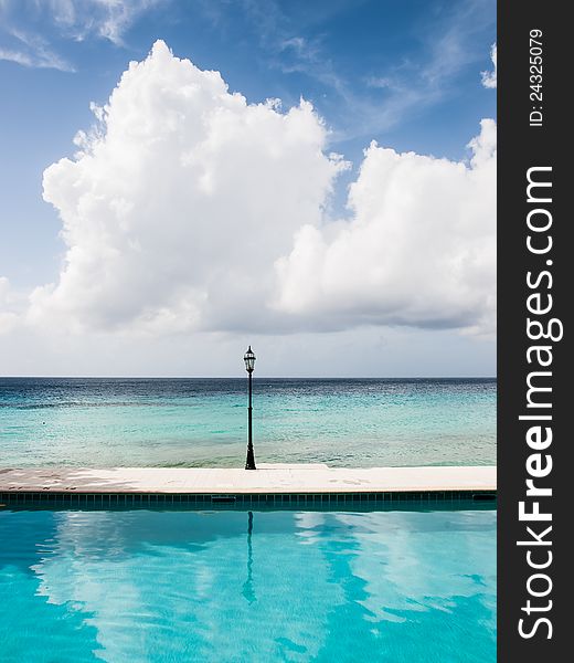 Unusual seascape with a lamp, crystal clear water and a deep blue sky with a big cloud.