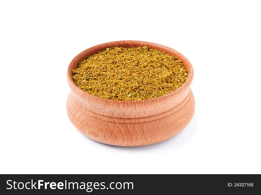 Mixture of dry spices in a wooden salt-cellar on a white background