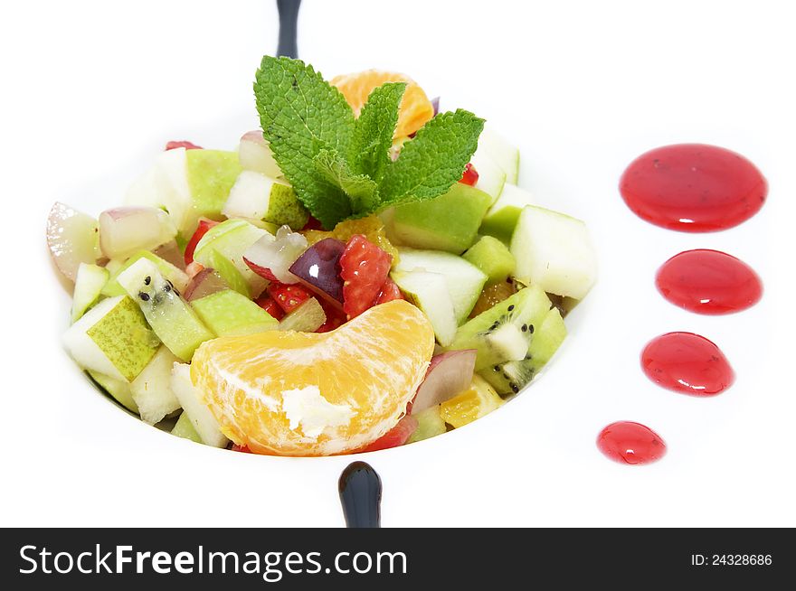 Fruit salad decorated with mint on a white plate. Fruit salad decorated with mint on a white plate