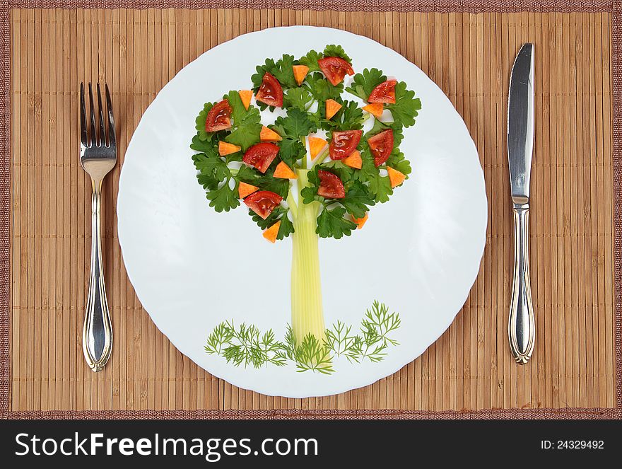 Tree of parsley and celery stalks with a lawn grass and fruit on a plate