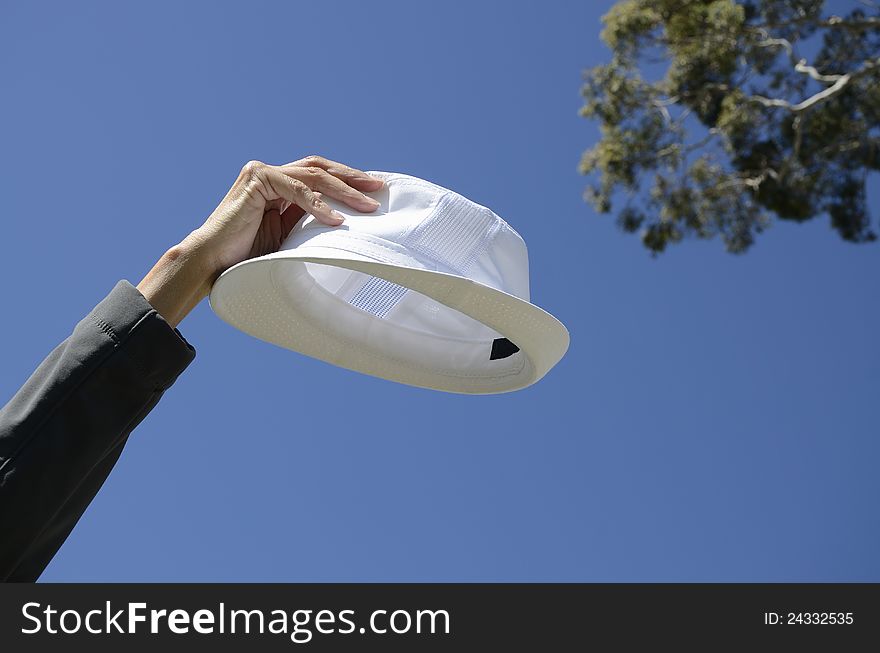 White hat held up in the air in one hand. White hat held up in the air in one hand