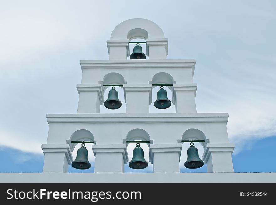 Six metal bells at the wall with cloudy sky