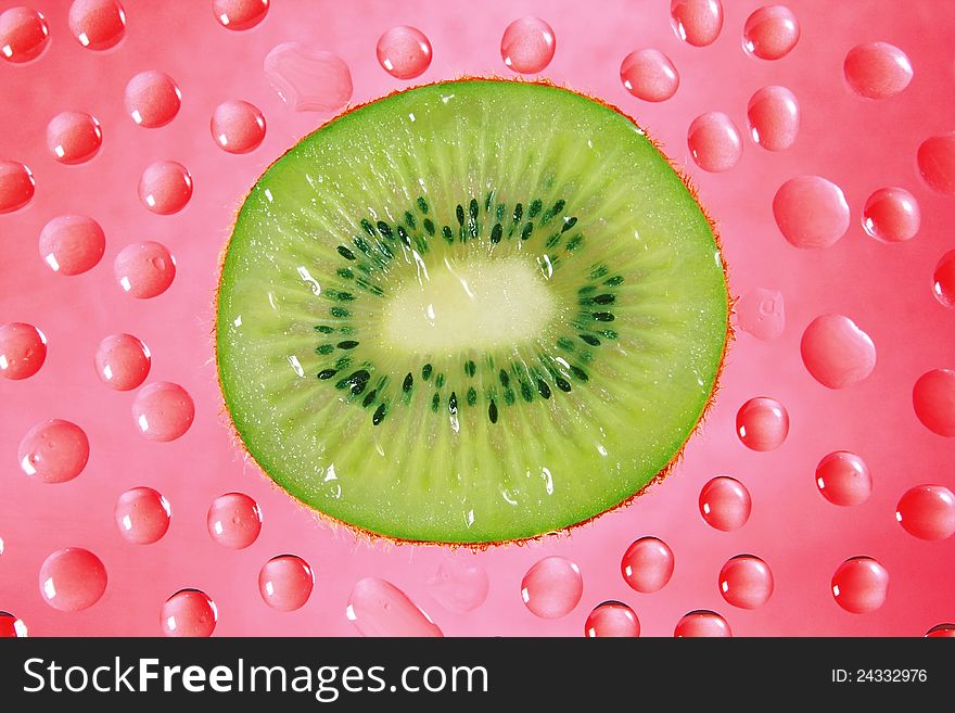 A fresh slice of kiwi fruit in red background drops.