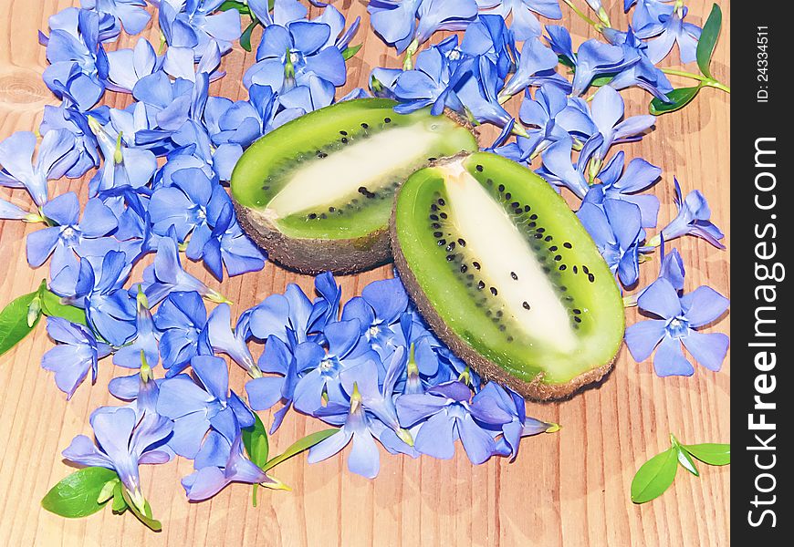 Halved juicy kiwi fruit and lots of blue flower. Halved juicy kiwi fruit and lots of blue flower