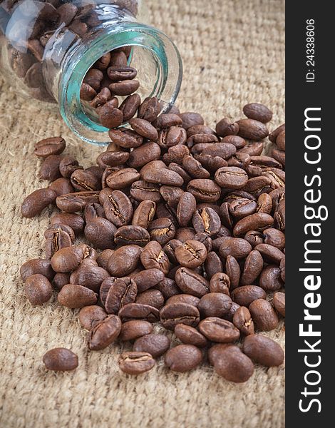 Coffee beans spilled out from glass little jar