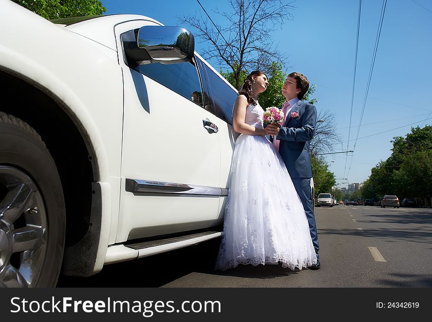 Happy bride and groom about wedding limousine