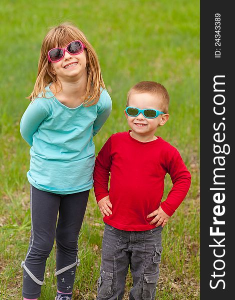 Brother and sister posing outside with sunglasses on their eyes on beautiful spring day. Brother and sister posing outside with sunglasses on their eyes on beautiful spring day.