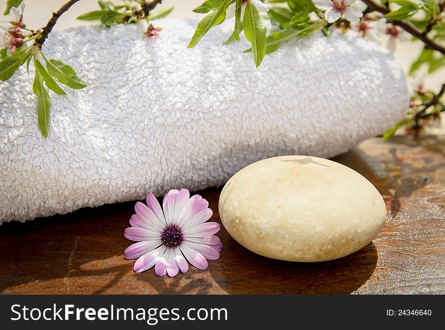 Towel, round stone, flower and vegetation on a wood table. Towel, round stone, flower and vegetation on a wood table.