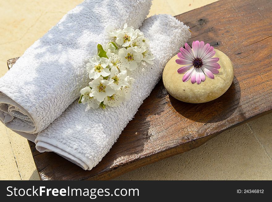 Towel, round stone and flower on a wood table in a spa. Towel, round stone and flower on a wood table in a spa.