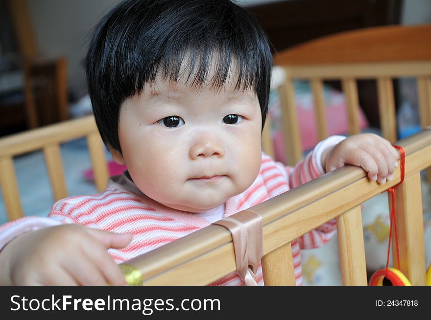 A 11 months chinese Baby girl standing on the bed