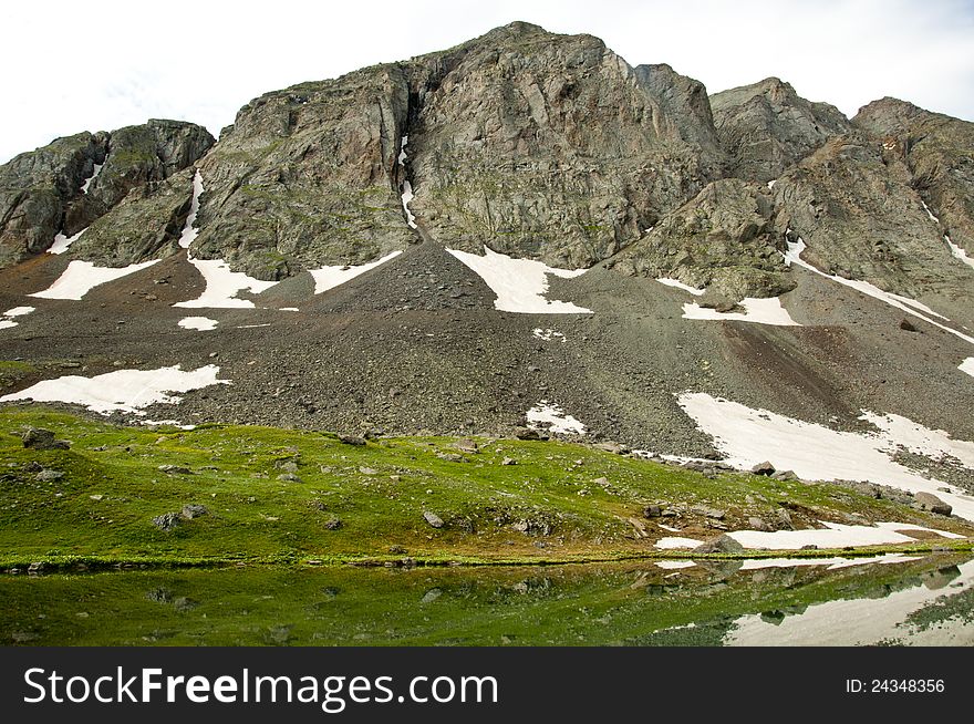 Melting snow and water reflections in a mountain lake. Melting snow and water reflections in a mountain lake.