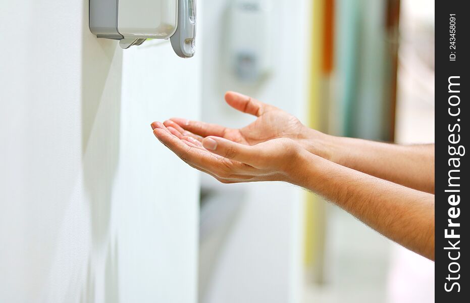 Hands under an automatic wall mounted sanitiser dispenser to get the hands sanitiser. Hands under an automatic wall mounted sanitiser dispenser to get the hands sanitiser.