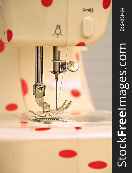 Close up photo of a modern electric sewing machine with a red polka dot design. Close up photo of a modern electric sewing machine with a red polka dot design.