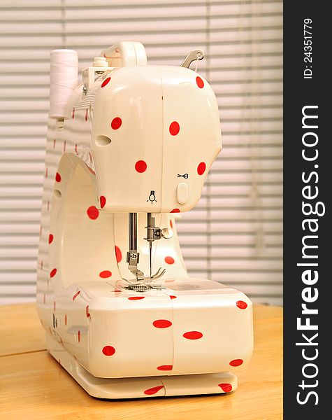 Photo of a modern electric sewing machine with a red polka dot pattern design. Photo of a modern electric sewing machine with a red polka dot pattern design.