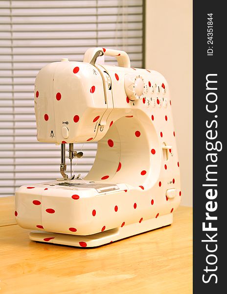 Photo of a modern electric sewing machine with a red polka dot pattern. Photo of a modern electric sewing machine with a red polka dot pattern.