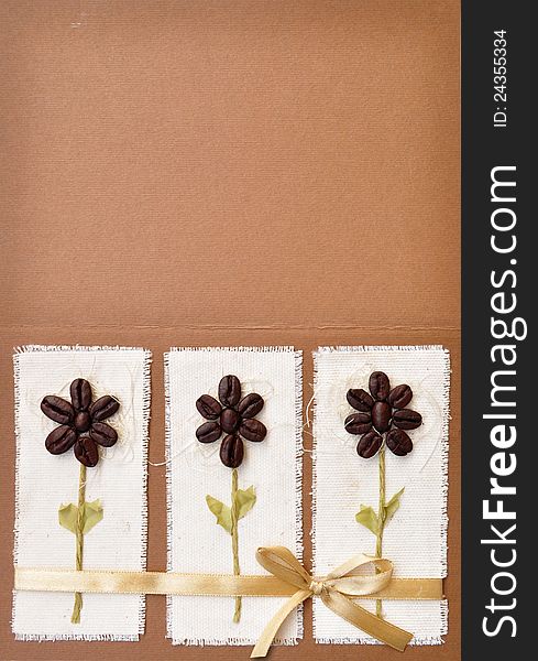 Handmade paper card with coffee beans flower design and a bow. Album book cover abstract background.
