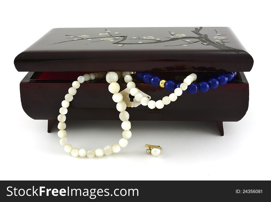 Jewelry box with pearl necklaces falling over white background